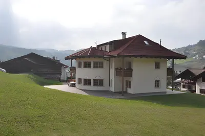 a white house with a brown roof on a hill at Apartments Konstanze in Pramauron