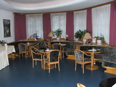 a dining room with two tables and chairs and two portraits at Hotel Bachmann in Villabassa