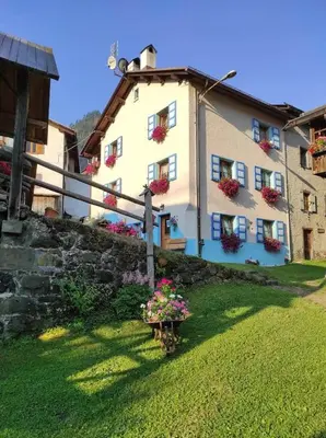 a white house with flowers in a yard at Ciesa del Selmo Faure in Sottoguda