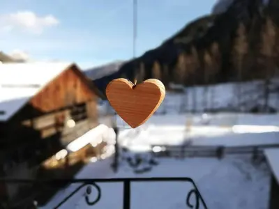 a wooden heart is hanging on a balcony at Ciesa del Selmo Faure in Sottoguda
