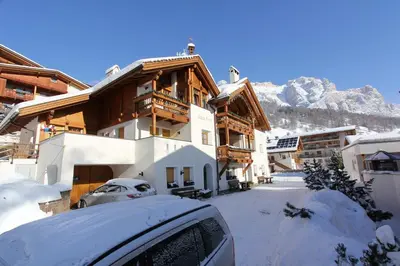 a building with a car parked in the snow at Residence Vajolet San Cassiano in San Cassiano