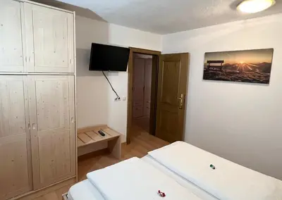 a room with two beds and a television in it at Residence Vajolet San Cassiano in San Cassiano