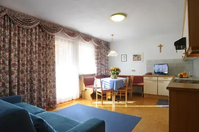 a living room with a couch and a table and a kitchen at Residence Vajolet San Cassiano in San Cassiano