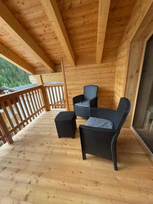 a screened porch with two chairs and a table at Residence Vajolet San Cassiano in San Cassiano