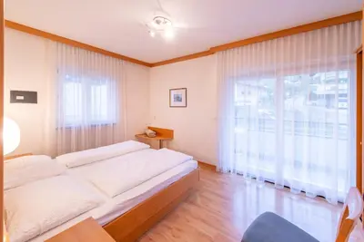 a bedroom with a large bed and a large window at Angerhof in Caldaro