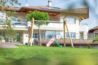 a playground in a yard in front of a house at Angerhof in Caldaro