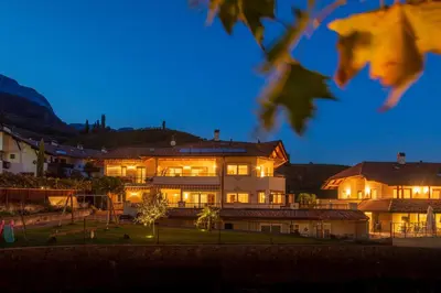 a large house with lights on at night at Angerhof in Caldaro