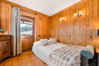 a bedroom with wooden walls and a bed with a window at Chalet Mortisa, Cortina design apartment in Col