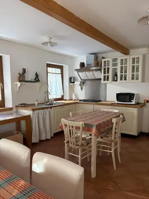a kitchen with a table and chairs and a kitchen with white cabinets at Mezzodì Locazione Turistica in Colcerver