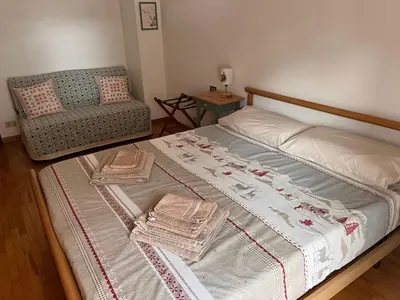 a bed with two blankets and a chair in a room at Angolo relax in Cencenighe