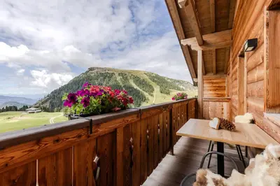 a balcony of a cabin with a table and flowers at Zischgalm in Obereggen