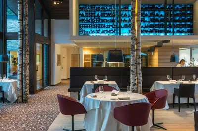a restaurant with white tables and chairs and a staircase at Terra - The Magic Place Relais & Châteaux in Sarntal