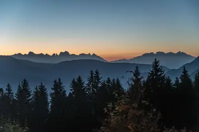 a sunset in the mountains with trees in the foreground at Terra - The Magic Place Relais & Châteaux in Sarntal