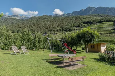 a playground with two chairs and a table and a swing at Baumgartnerhof in Lagundo