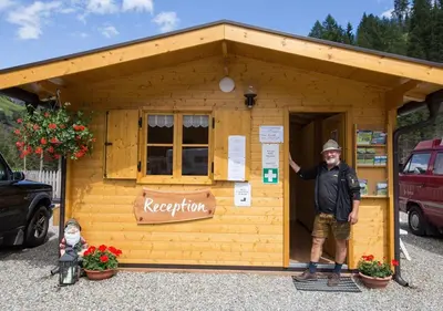 a man standing in front of a small shed at Camping Bergkristall in Moso