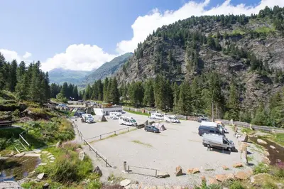 a parking lot with cars parked in front of a mountain at Camping Bergkristall in Moso