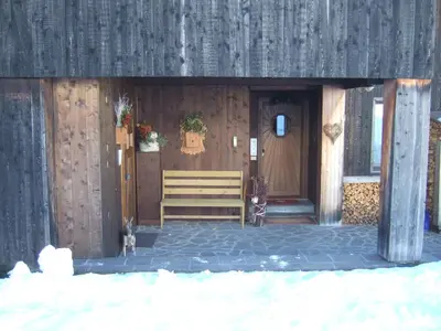 a wooden building with a bench in front of it at Cristallo & Faloria Suite Apartments in Cortina dʼAmpezzo