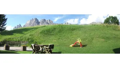 a girl is sitting on a grassy hill at Cristallo & Faloria Suite Apartments in Cortina dʼAmpezzo
