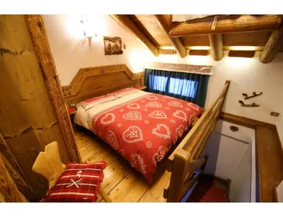 a bedroom with a red bed in a house at Cristallo & Faloria Suite Apartments in Cortina dʼAmpezzo
