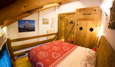 a bedroom with a red bed and a wooden cabinet at Cristallo & Faloria Suite Apartments in Cortina dʼAmpezzo