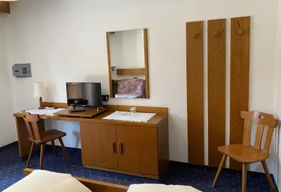 a room with a desk with a computer and a mirror at Hotel Friedemann in Rasùn di Sotto