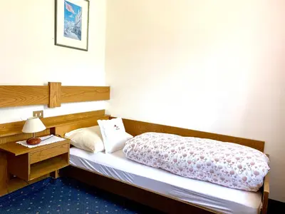 a hotel room with a bed and a night stand at Hotel Friedemann in Rasùn di Sotto