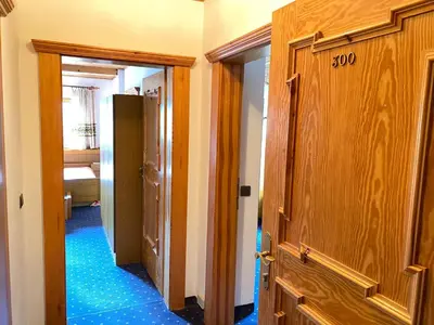 a hallway with a door and a room with blue floors at Hotel Friedemann in Rasùn di Sotto