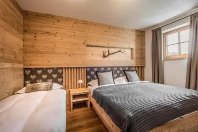 two beds in a room with wooden walls at Mountain Chalet Pia in La Valle