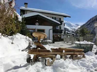a bench in the snow in front of a house at Gasthof Innerwalten in San Leonardo in Passiria