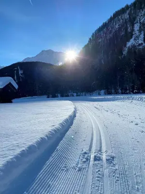 a snow covered road with the sun in the background at Gasthof Innerwalten in San Leonardo in Passiria