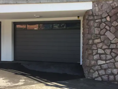 a garage door of a house with a stone wall at Pra Ciarea Apartments in Ortisei
