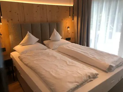 a bedroom with two beds with white sheets and a window at Pra Ciarea Apartments in Ortisei