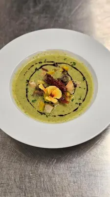 a white plate with a bowl of soup on a table at Berghotel zum Zirm in Collalbo