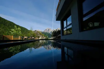 a pool of water with mountains in the background at Vidor Resort in Pozza di Fassa