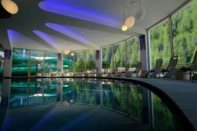 a swimming pool in a hotel with chairs and windows at Vidor Resort in Pozza di Fassa