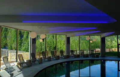 a room with a pool and chairs and a large window at Vidor Resort in Pozza di Fassa