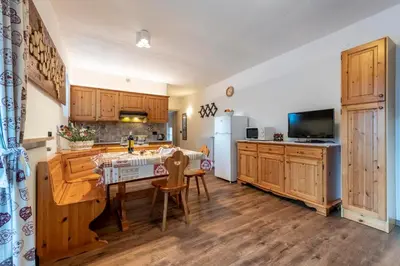 a kitchen with wooden cabinets and a table with chairs at Appartamenti Residence La Roggia in Pozza di Fassa