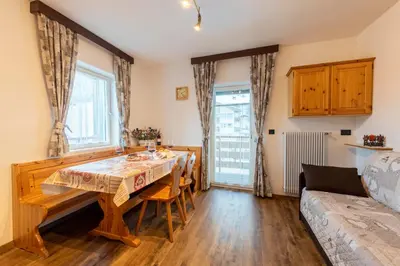 a dining room with a table and chairs and a couch at Appartamenti Residence La Roggia in Pozza di Fassa