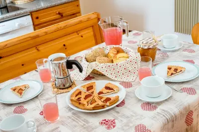 a table with a basket of bread and pastries on it at Appartamenti Residence La Roggia in Pozza di Fassa