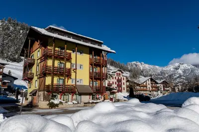 a building in the snow with a pile of snow at Appartamenti Residence La Roggia in Pozza di Fassa