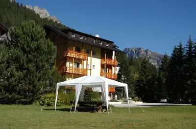 a tent in a field in front of a building at Appartamenti Residence La Roggia in Pozza di Fassa