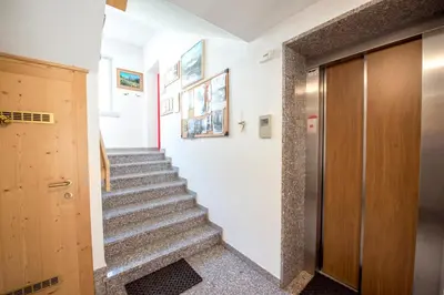 a hallway with stairs and a wooden door at Appartamenti Residence La Roggia in Pozza di Fassa
