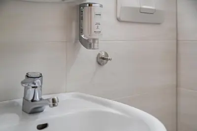 a bathroom sink with a soap dispenser on the wall at Residence Condor in Maranza