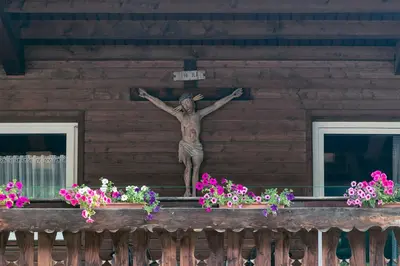a statue of a man on the side of a building with flowers at Gasthof Mesnerwirt in Auna di Sopra