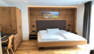 a bedroom with a large bed with a wooden wall at B&B Obermair in Brunico