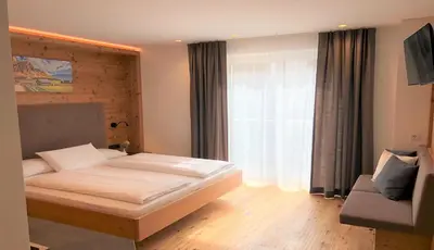 a bedroom with a bed and a large window at B&B Obermair in Brunico
