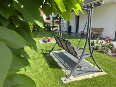 a metal swing in a yard with green grass at B&B Obermair in Brunico