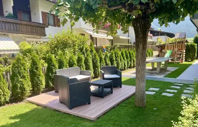 a garden with two chairs and a table and a tree at B&B Obermair in Brunico