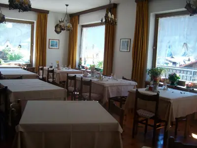 a restaurant with tables and chairs with white tablecloths at Hotel Nevada in Campitello di Fassa