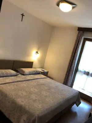 a bedroom with two beds and a cross on the wall at Hotel Nevada in Campitello di Fassa